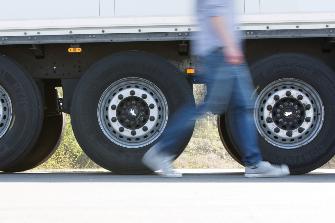 
Een bestuurder passeert voor de assen van zijn vrachtwagen.