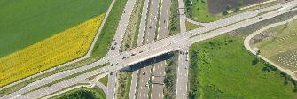 
Imagen aérea de dos carreteras sujetas al pago de peaje: un puente de una carretera nacional pasa por encima de una autopista