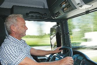 
Un conductor de camión detrás del volante; encima del parabrisas hay montado un equipo de vehículo.