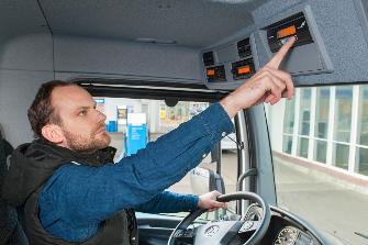 
Șoferul din cabina unui autocamion utilizează o unitate de bord