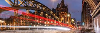 
Estelas luminosas dinámicas de vehículos al amanecer en un puente del barrio de Speicherstadt, en Hamburgo