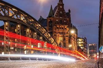 
Estelas luminosas dinámicas de vehículos al amanecer en un puente del barrio de Speicherstadt, en Hamburgo