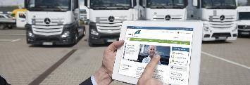 
A courier in front of his truck holding a tablet, with the screen showing the Toll Collect customer portal.