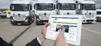 
Ein Spediteur hält vor seinen Lkw ein Tablet, auf dem Bildschirm das Toll Collect Kunden-Portal.