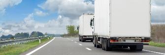 
Rear view of two trucks driving toward the horizon on a motorway