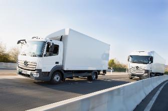 
Twee tolplichtige vrachtwagens rijden achter elkaar op een autosnelweg.