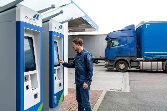 
Řidič nákladního automobilu obsluhuje mýtný terminál na čerpací stanici.