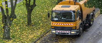 
Ein nicht mautpflichtiges Fahrzeug zur Straßenreinigung kehrt Herbstlaub auf